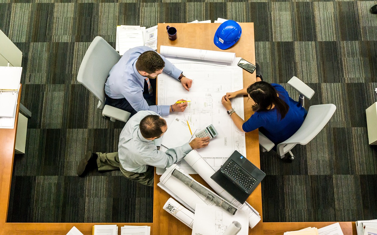 Three business professionals seated at a table performing work.