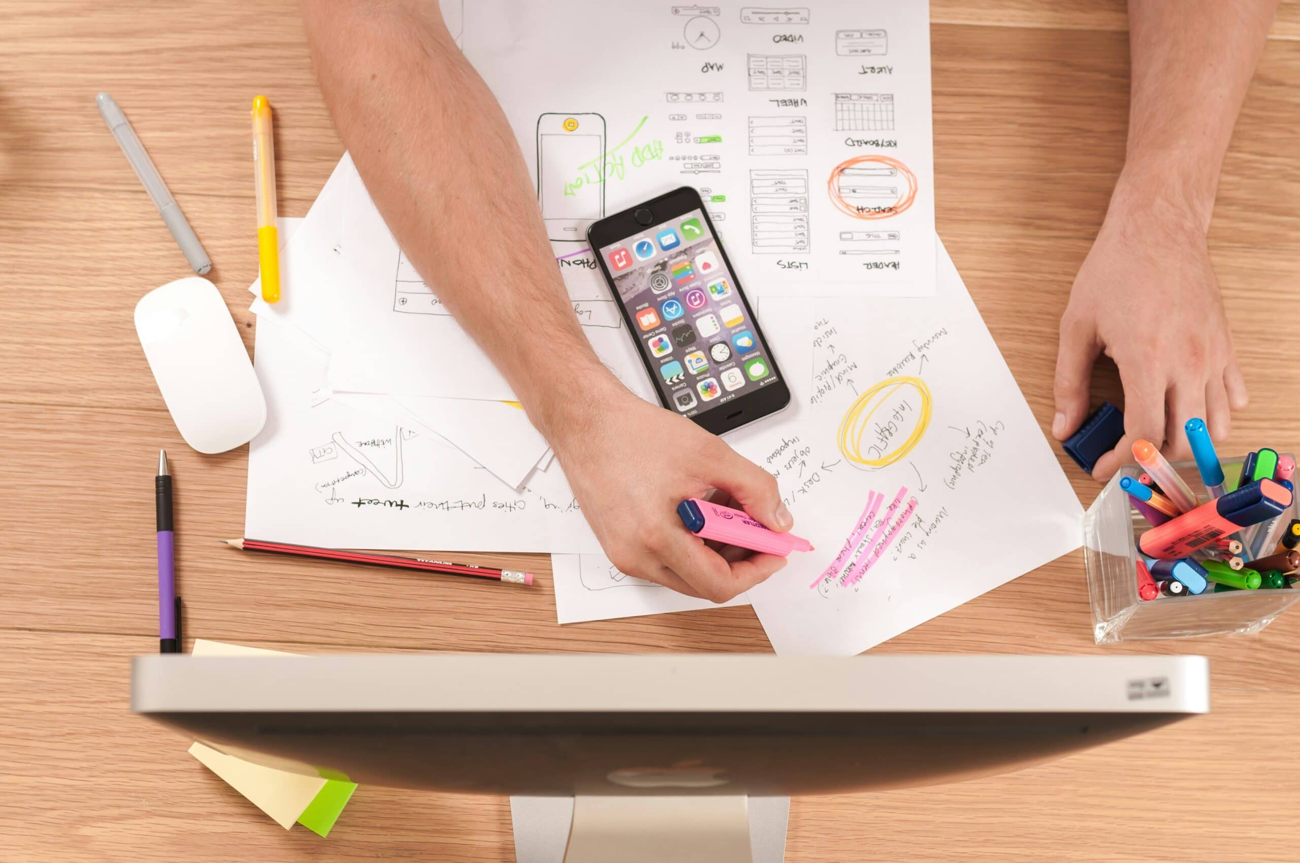 A person's hands atop paperwork while writing and creating a complex plan.